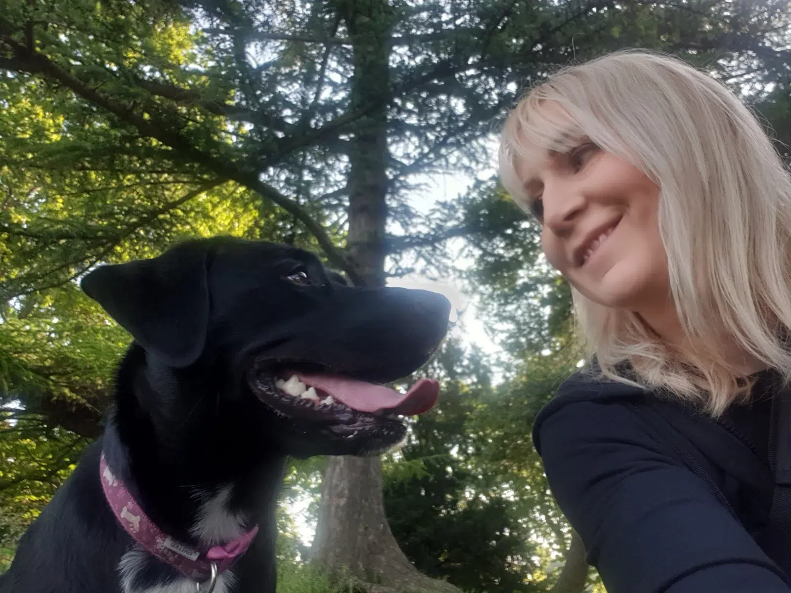 Michelle beside a black dog outdoors