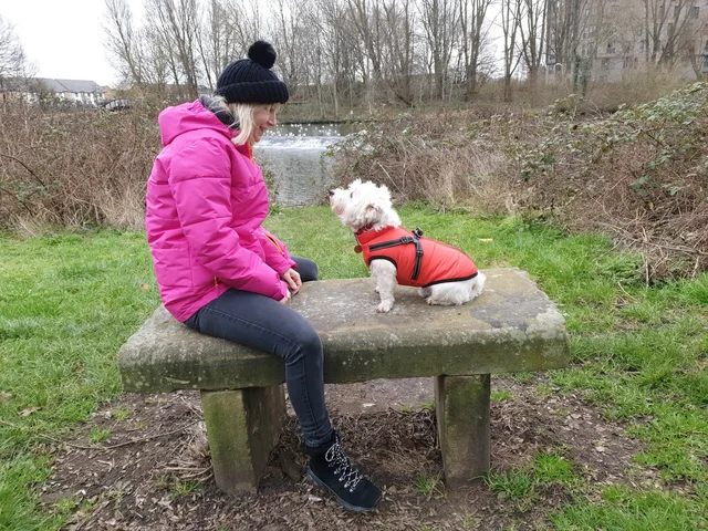 Michelle sitting beside a small dog on a winter walk