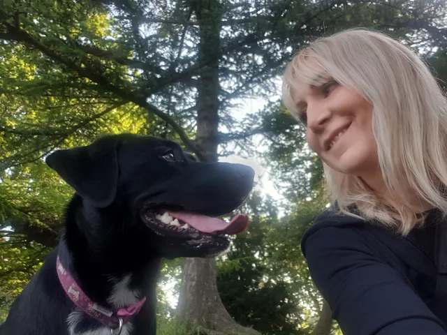 Michelle beside a black dog outdoors