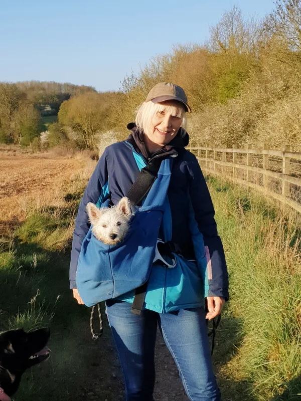 Michelle carrying a small dog outdoors